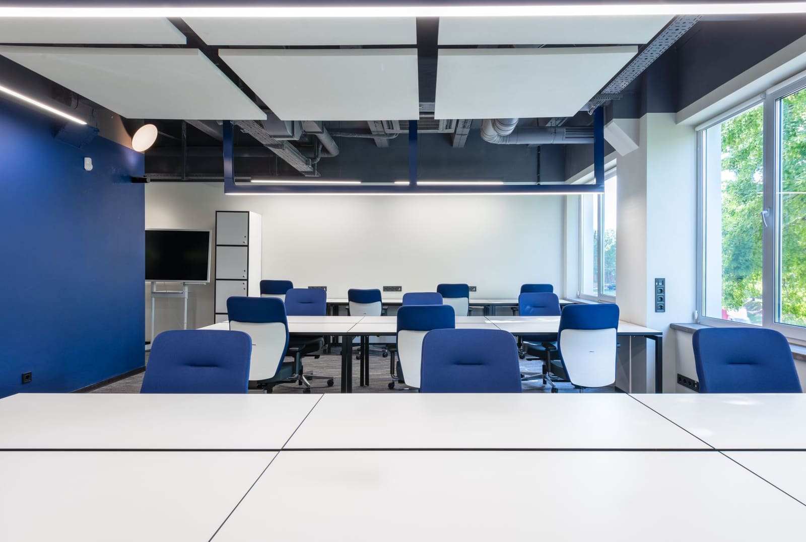A bright open workspace with white desks and blue chairs